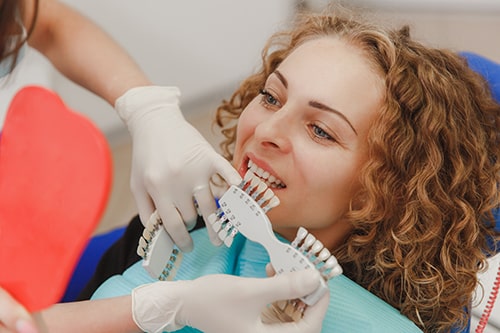 dentist comparing patient s teeth shade with samples bleaching treatment